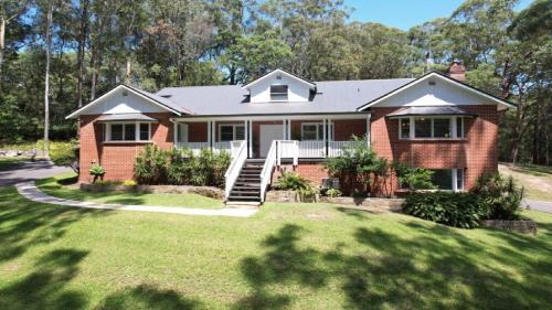 a red brick house with a staircase in a yard at Nirvana Estate Macmasters Beach in Macmasters Beach