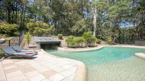 a swimming pool with a chaise lounge and a swimming pool at Nirvana Estate Macmasters Beach in Macmasters Beach