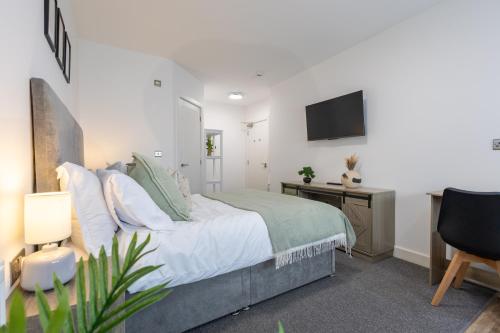 a bedroom with a bed and a tv on the wall at Derwent Court Aparthotel in Derby