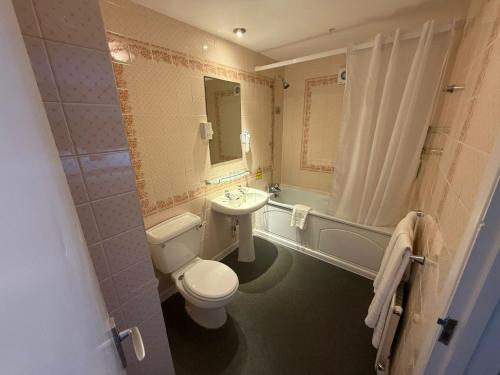 a bathroom with a toilet and a sink and a tub at Raven Hotel by Greene King Inns in Hook