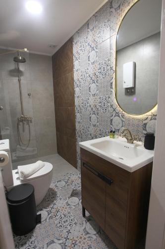 a bathroom with a sink and a toilet and a mirror at Villa Korzo in Bitola