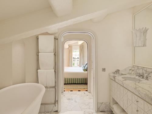 a white bathroom with a tub and a sink at Hotel Byblos Saint-Tropez in Saint-Tropez