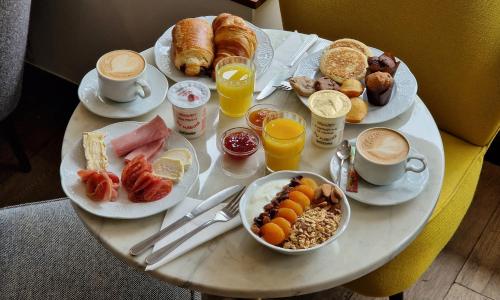 a table with plates of breakfast foods and drinks at Hotel André Latin in Paris