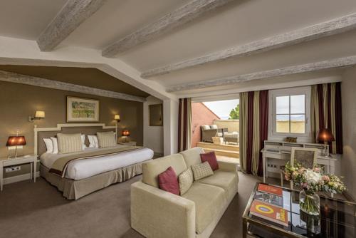 a large bedroom with a bed and a couch at Hotel Byblos Saint-Tropez in Saint-Tropez