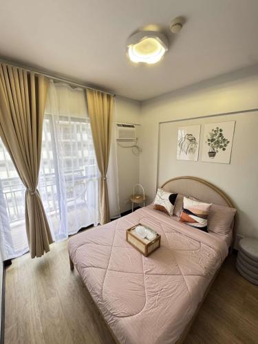 a bedroom with a large bed with a large window at Alea Residences 1 Bedroom Condo with Pool View Balcony in Manila