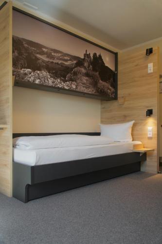 a bedroom with a bed with a picture on the wall at Hotel & Tagungszentrum Blaubeuren - Hessenhöfe in Blaubeuren