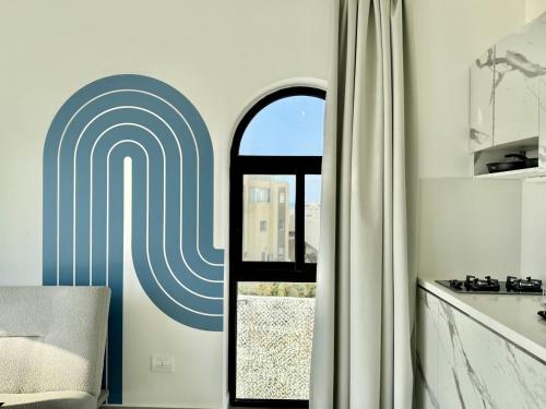 a kitchen with a window and a door with a spiral at Butterwave | 1BR Jacuzzi & Terrace in Kfar Aabida in Fad‘ūs