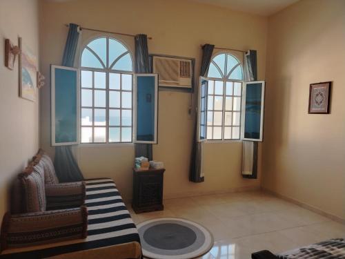 Una sala de estar con tres ventanas y una silla. en Bustan Shells House, en Mascate