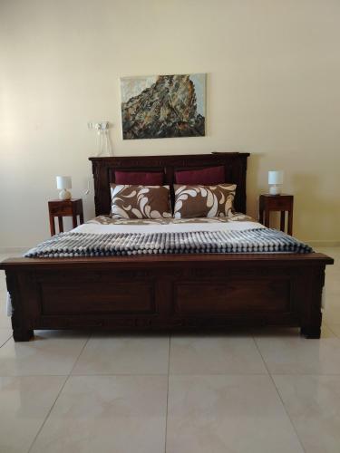 Una gran cama de madera con almohadas en un dormitorio. en Bustan Shells House, en Mascate