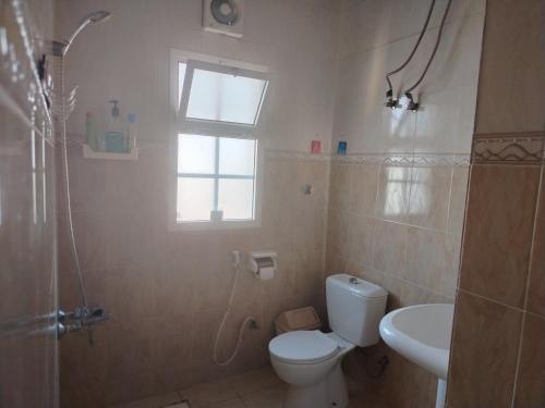 Un baño con inodoro, ducha y lavabo. en Bustan Shells House, en Mascate
