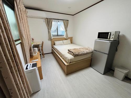 a small bedroom with a bed and a refrigerator at Bon House Tokyo Private Luxury Retreat with Free Parking Reservation Required in Tokyo