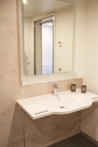 a bathroom with a white sink and a mirror at Ferienhaus - Kann in Vollerwiek