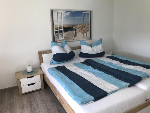 a bedroom with a bed with blue and white pillows at Ferienhaus - Kann in Vollerwiek