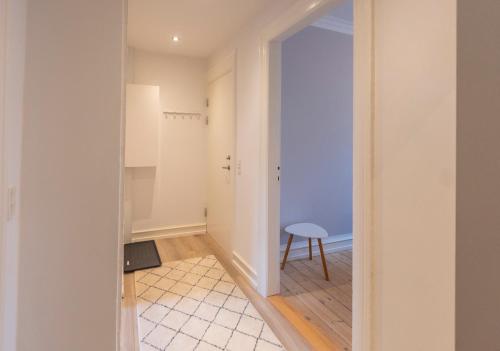 a hallway with a door leading into a room with a stool at Odinsvej Apartments - by Central Lyngby Apartments in Kongens Lyngby