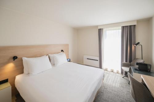 a hotel room with a large white bed and a window at Begijnhof Hotel in Leuven
