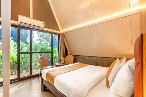 a bedroom with a bed and a large window at Alaya stays Inara Retreat 1-Cottage with a Mezzanine Loft, Shared Pool, and Garden in Bangalore