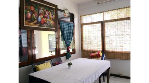 a dining room with a white table and two windows at Many Trees in Bangkok