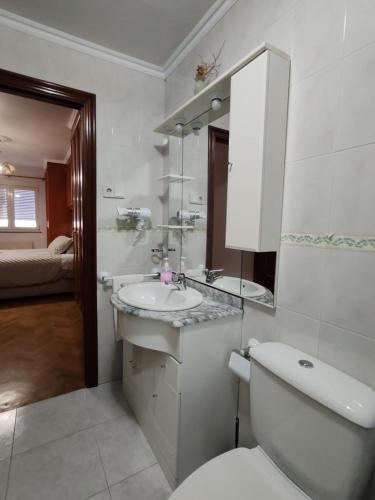 a bathroom with a sink and a toilet and a mirror at Apartamentos Quien Anda Ahí Ribadeo in Ribadeo