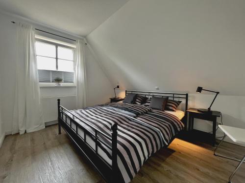 a bedroom with a bed with a striped comforter and a window at Dorf 36 in Ording