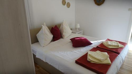 a white bed with red and white pillows on it at Apartments Lena in Podgora