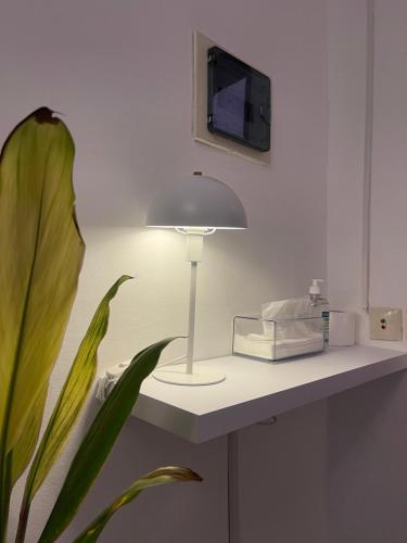 una lampada appoggiata su un tavolo con una pianta di Résidence chez-moi a Moosou