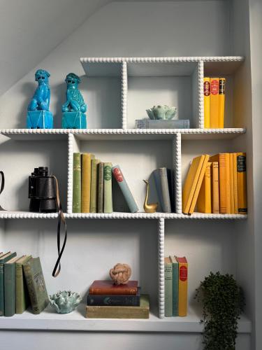 a white book shelf with books and vases on it at NEW - Periwinkle Townhouse - 3-min walk from Bath Spa Station in Bath