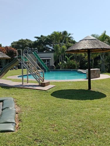 a swimming pool with a slide and an umbrella at Umzumbe Chalets Share Block ltd in Umzumbe