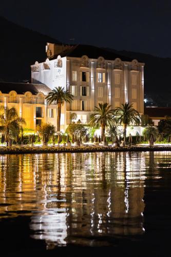 ein Gebäude mit Palmen vor einem Gewässer in der Unterkunft Hotel Palma in Tivat