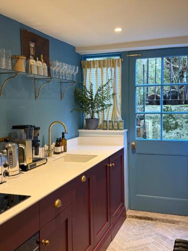 a kitchen with a sink and a blue wall at NEW - Periwinkle Townhouse - 3-min walk from Bath Spa Station in Bath