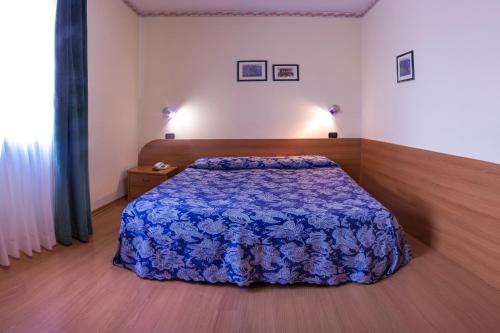 a bedroom with a bed with a blue blanket at Hotel Sporting in Casarsa della Delizia