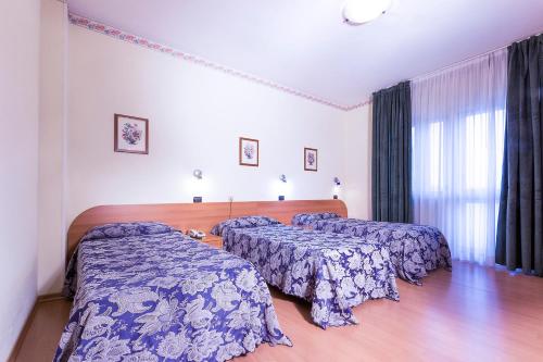 a hotel room with two beds and a window at Hotel Sporting in Casarsa della Delizia