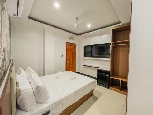 a white bedroom with a bed and a television at The Town - By Namal in El Nido
