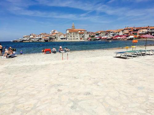 a group of people sitting on a beach near the water at Apartment Umag Nelly in Umag