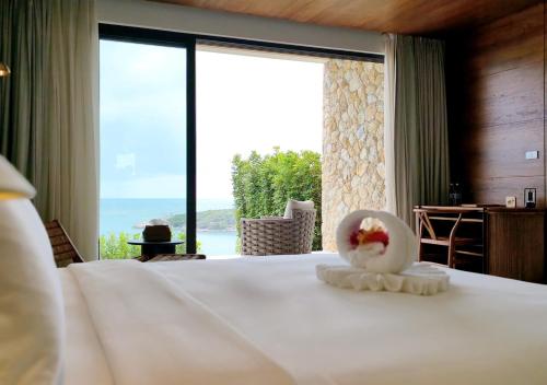 a bedroom with a bed with a view of the ocean at Cape Azure Resort Samui by Thalsea in Plai Laem