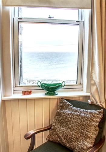 a window with a green bowl on a chair in front of the ocean at Fisherman's Cottage in Cockenzie