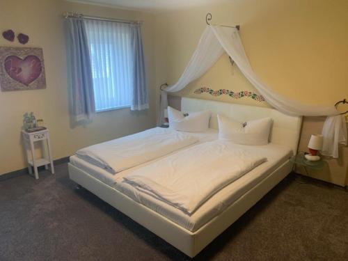 a bedroom with a large white bed with a canopy at Hotel Schwarzes Ross Siebenlehn in Siebenlehn