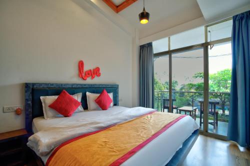 a bedroom with a bed with red pillows and a balcony at Baga Riverview 2BHK Mayonna Apartment in Baga