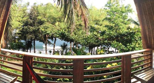 a hammock on a balcony looking out at the ocean at Villa Monyet Java in Batukaras