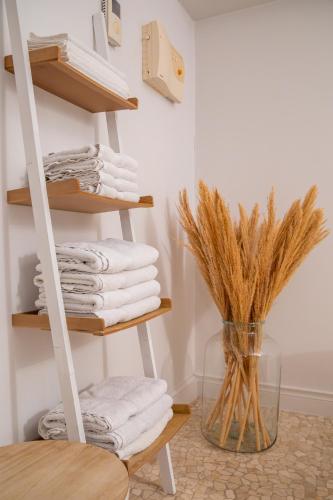 a shelf with towels and a vase with dry grass at Esplanada Studios in Genk