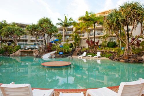a large swimming pool with chairs and a building at BreakFree Alexandra Beach in Alexandra Headland
