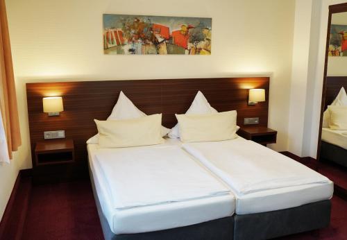 a hotel room with a bed with white pillows at Haus Sparkuhl Hotel Garni in Hannover