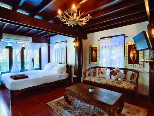 a bedroom with two beds and a table and a tv at Huen Tip Viman Chiangmai in Ban Nong Ho