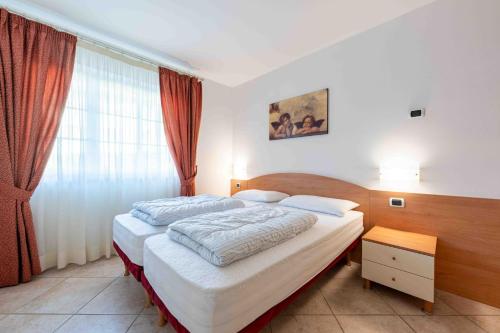a bedroom with two beds and a window at Cesa Primula in Canazei