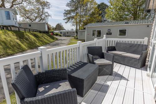 a porch with wicker chairs and tables and a fence at Hotel du Van - Rockley Park Caravan, Activities On-site in Poole