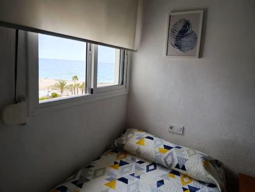 a bedroom with a bed and a window with the beach at Apartamento con vistas al mar! Comaruga in La Playa