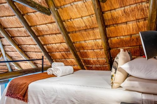 a bedroom with a bed in a thatched roof at Little Orvyll's Studio- Near Kruger National Park, you can add up to six guests at our Larger Property Croc Orvyll's Kruger Lodge and all stay in one location in Marloth Park