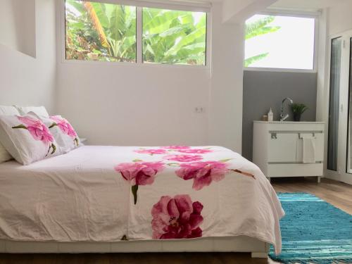 a bedroom with a bed with pink flowers on it at Rochinha Cozy Home in Funchal