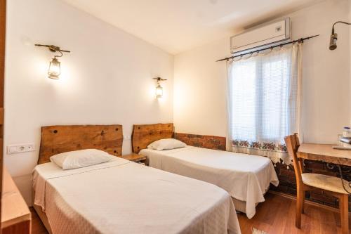 una stanza con due letti, un tavolo e una finestra di Amazon Petite Palace a Selçuk