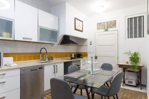 a kitchen with white cabinets and a glass table and chairs at Rochinha Cozy Home in Funchal