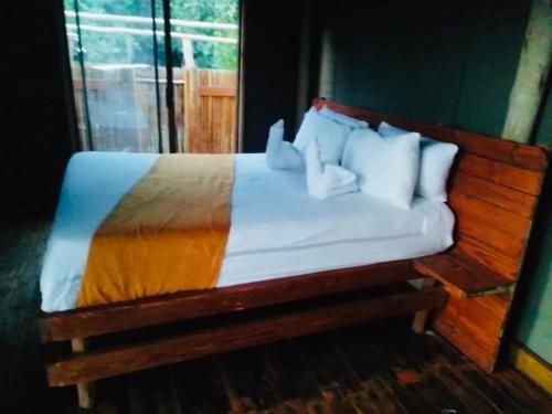 un letto con testiera in legno e cuscini bianchi di Nyati House a Khwai